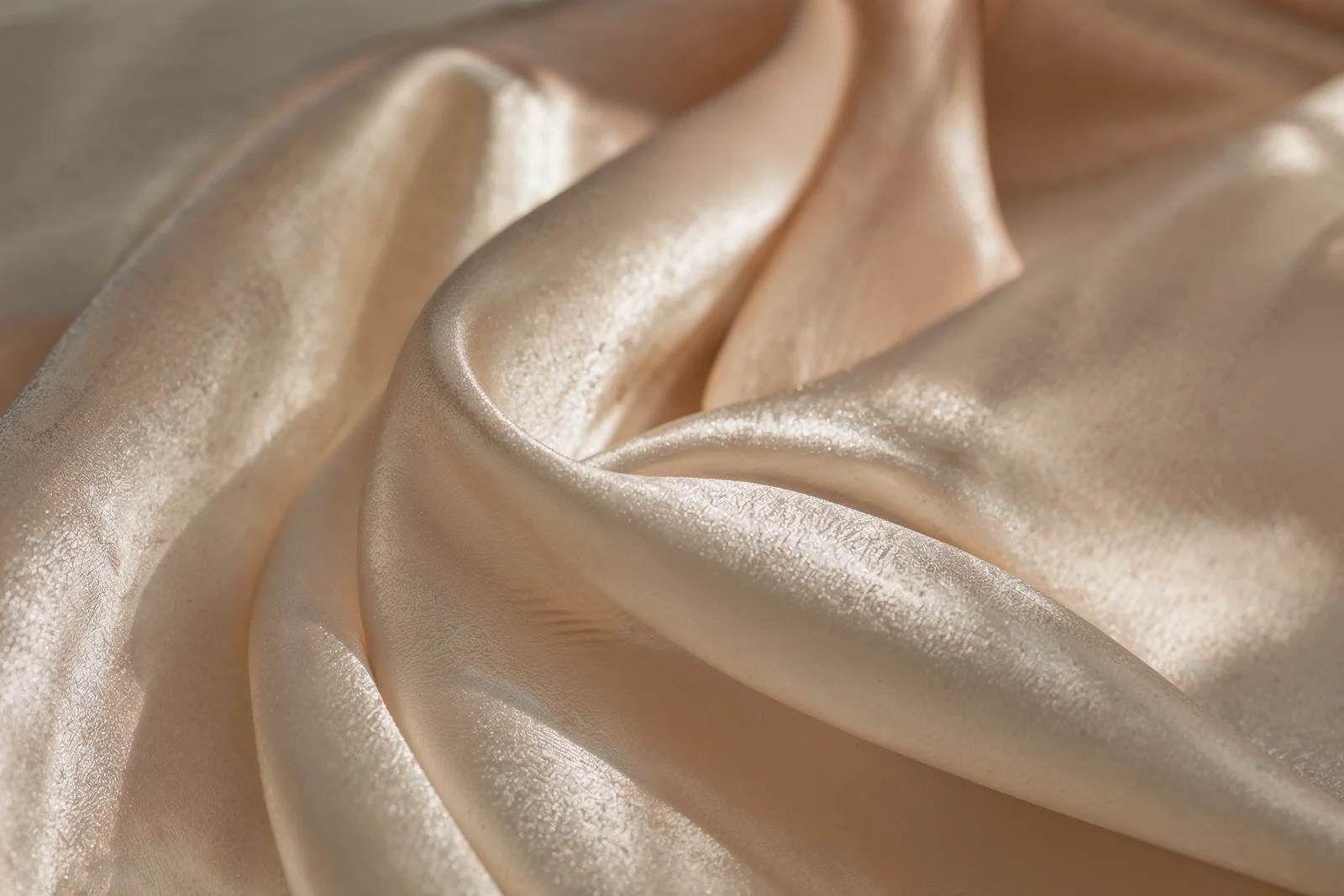 Kıvrımlı krem satin kumaş yakın çekim, ışık-gölge oyunu.